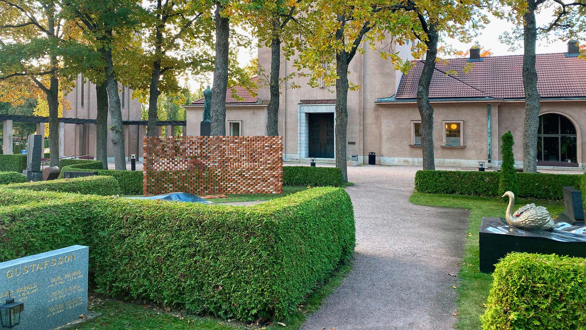 A wall made of bricks in the cemetery, through which you can see.